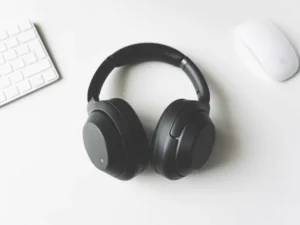 Wireless headphones on a white desk beside a keyboard and mouse