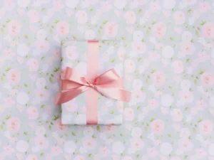 A gift box wrapped in floral paper with a pink satin bow