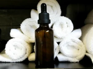 Rolled white towels with an amber glass dropper bottle