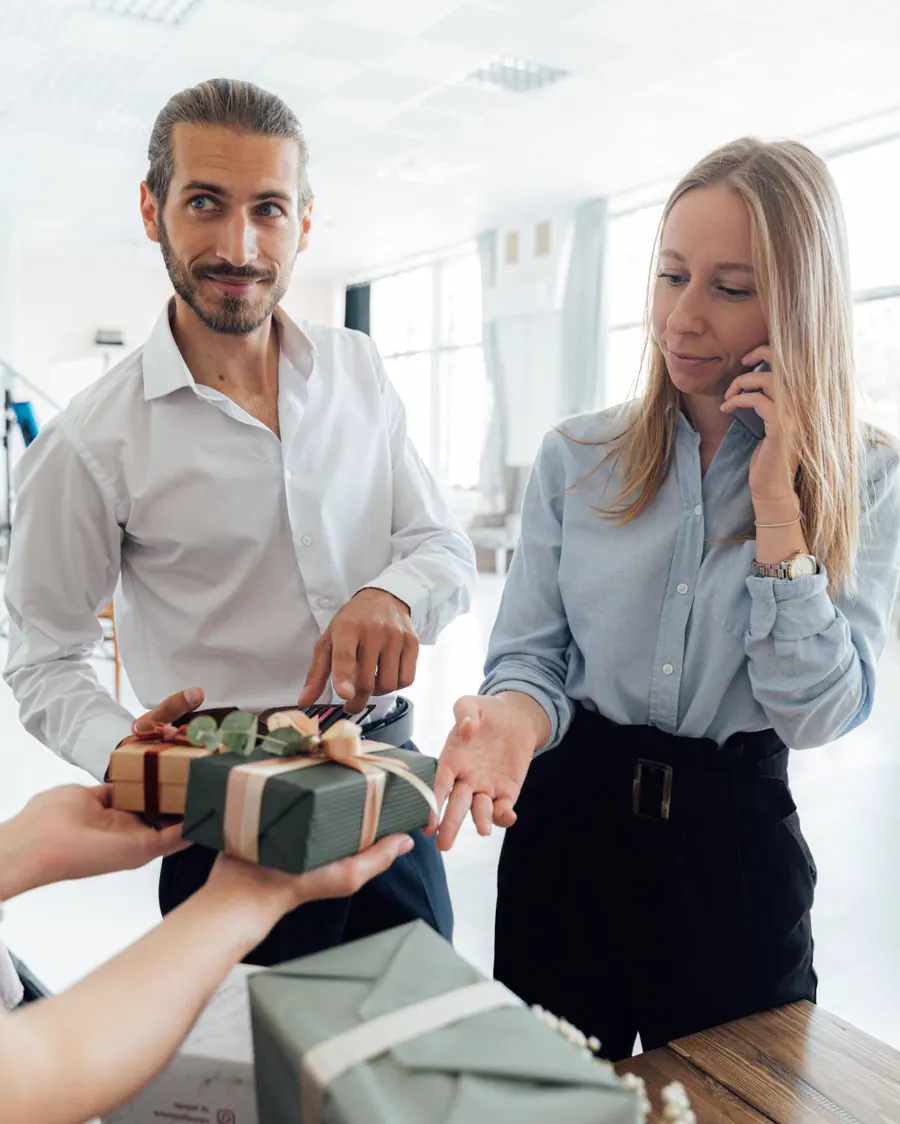 A colleague handing a wrapped gift box to a coworker in an office