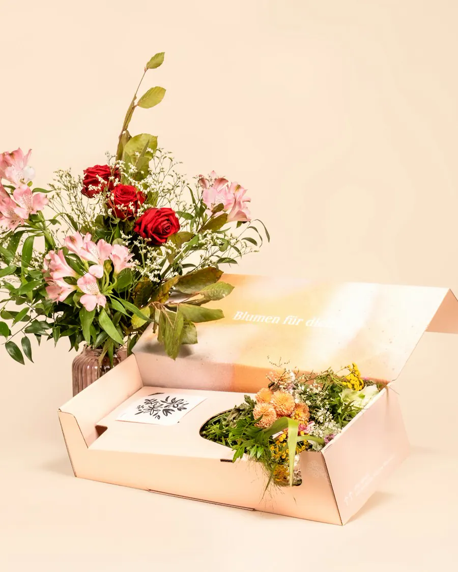 Fresh flowers beside an open gift box with a card